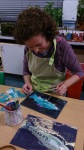 woman painting glue during a paper collage lesson